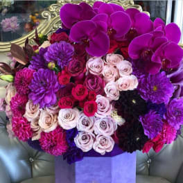 Bouquet of purple orchids, roses, and dahlias in a lavender box