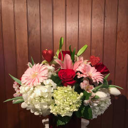 Bouquet of pink and red flowers in a dark vase with glitter heart picks