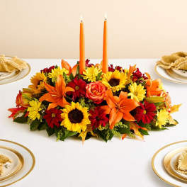 Autumn centerpiece with orange candles and mixed flowers on a table