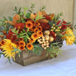 Autumn floral arrangement in a wooden box with orange and yellow blooms
