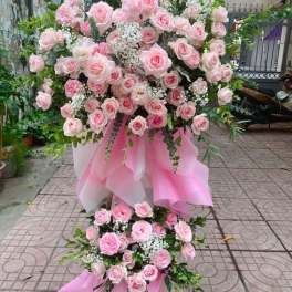 Large pink rose arrangement with white filler flowers and pink draping
