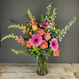 Mixed bouquet of pink gerbera daisies and orange roses in a glass vase