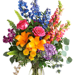 Colorful bouquet of roses, lilies, and snapdragons in a glass vase