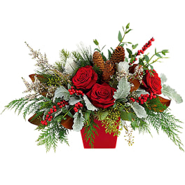 Red roses in a red container with pinecones and berries