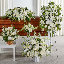 White funeral floral arrangements around a casket, including a standing spray and bouquets