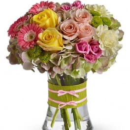 Mixed bouquet of roses, gerbera daisies, and hydrangeas in a glass vase