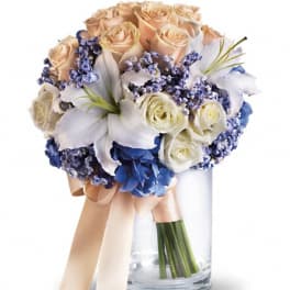Bouquet of peach and white roses with blue flowers in a glass vase