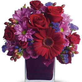 Red and purple mixed bouquet in a clear square vase