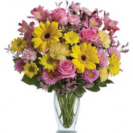 Mixed pink and yellow flowers in a clear glass vase