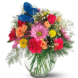 Mixed bouquet in a glass vase with a blue butterfly decoration