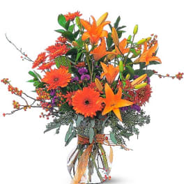 Orange lilies and gerbera daisies in a clear vase
