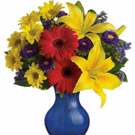 Colorful bouquet of lilies, gerbera daisies, and daisies in a blue vase
