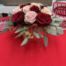 Red and blush roses arranged in a red gift box with ribbon