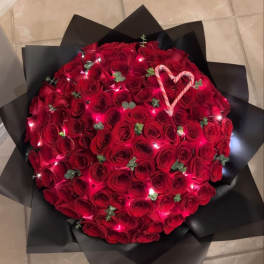 Large bouquet of red roses wrapped in black paper with a candy cane heart
