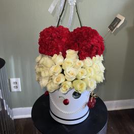 Red carnations and white roses in a white hatbox with pearl ribbon