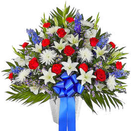 Large bouquet of red roses, white lilies, and blue flowers with a blue ribbon