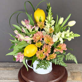 Mixed bouquet with lemons in a white mug-style vase