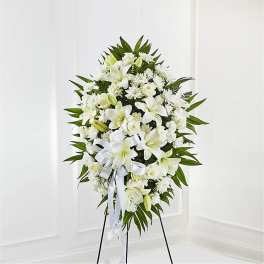 White floral standing spray on a black easel with a ribbon bow