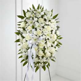 White funeral spray with roses and lilies on a stand