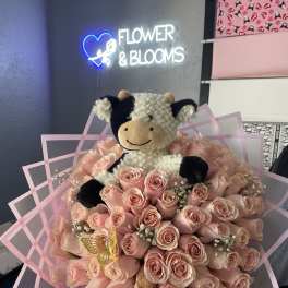 Pink rose bouquet with a plush cow topper and pink wrap