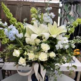White lilies and roses in a dark vase with striped ribbon