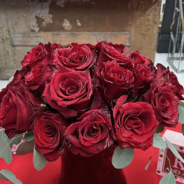 Bouquet of red roses in a dark vase with eucalyptus accents