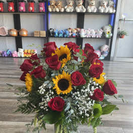Bouquet of red roses and sunflowers in a glass vase