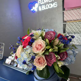 Mixed rose bouquet with blue hydrangeas in a round box