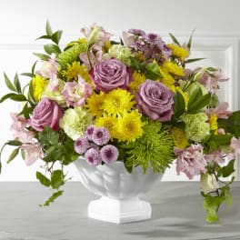 Mixed bouquet of pink roses and yellow chrysanthemums in a white pedestal vase