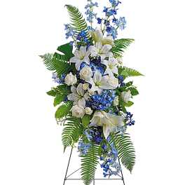 Tall standing floral spray with white lilies, white roses, and blue flowers