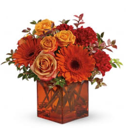 Orange and red flowers arranged in a square glass vase