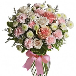 Pink and white rose bouquet in a glass vase with a pink ribbon