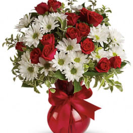 Red roses and white daisies in a red vase with a ribbon
