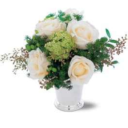 White roses arranged in a white vase with green filler