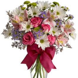 Bouquet of pink roses, white daisies, and alstroemeria in a glass vase with a ribbon