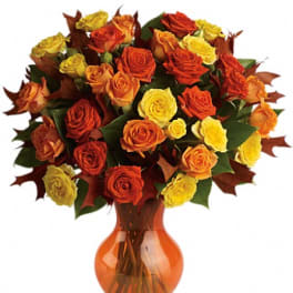 Bouquet of orange, red, and yellow roses in an amber glass vase