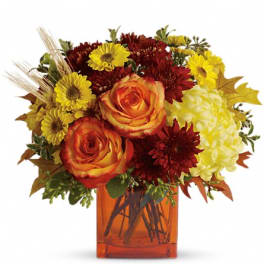 Autumn bouquet of orange roses, yellow daisies, and red mums in an amber vase