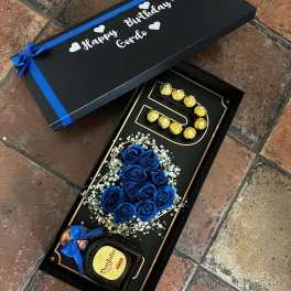 Gift box with blue roses, chocolates, and a bottle of Don Julio
