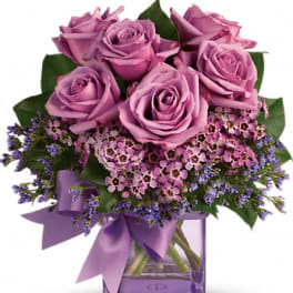 Lavender roses in a glass vase with purple ribbon