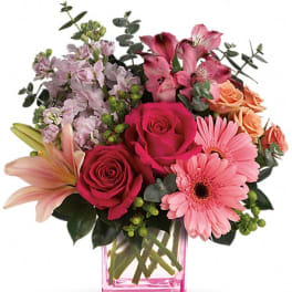 Bouquet of pink roses, lilies, and gerbera daisies in a pink glass vase