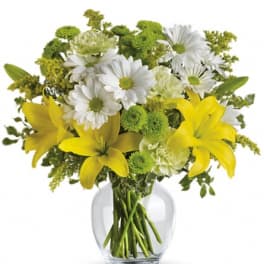 Yellow lilies and white daisies in a clear glass vase
