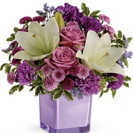 Purple and pink bouquet with white lilies in a lavender vase