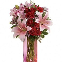 Pink lilies and red roses in a tall pink glass vase