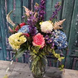 Colorful mixed bouquet in a glass vase with tall purple blooms