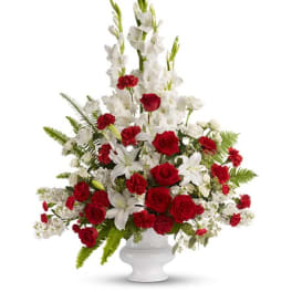 Tall red and white floral arrangement in a white pedestal vase