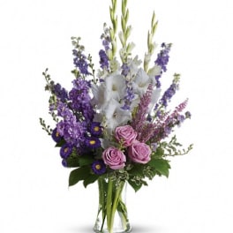 Tall bouquet of purple, white, and pink flowers in a clear glass vase