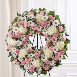 Pink and white floral wreath on a black stand
