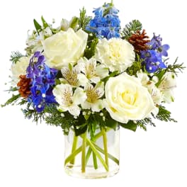 White roses and blue flowers arranged in a clear glass vase