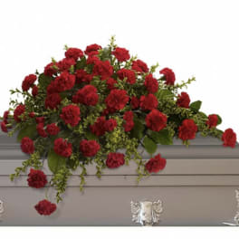 Long red carnation casket spray arranged atop a gray casket