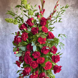 Tall cascading arrangement of red roses and carnations with green bells of Ireland.